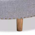 Pouf rotondo imbottito con piano trapuntato e bordatura con borchie