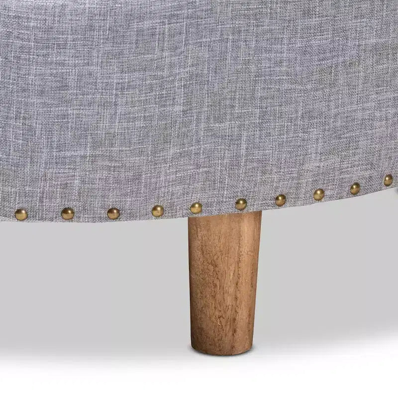 Pouf rotondo rivestito in tessuto, con parte superiore trapuntata e borchie decorative
