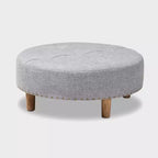 Pouf rotondo imbottito con piano trapuntato e bordatura con borchie
