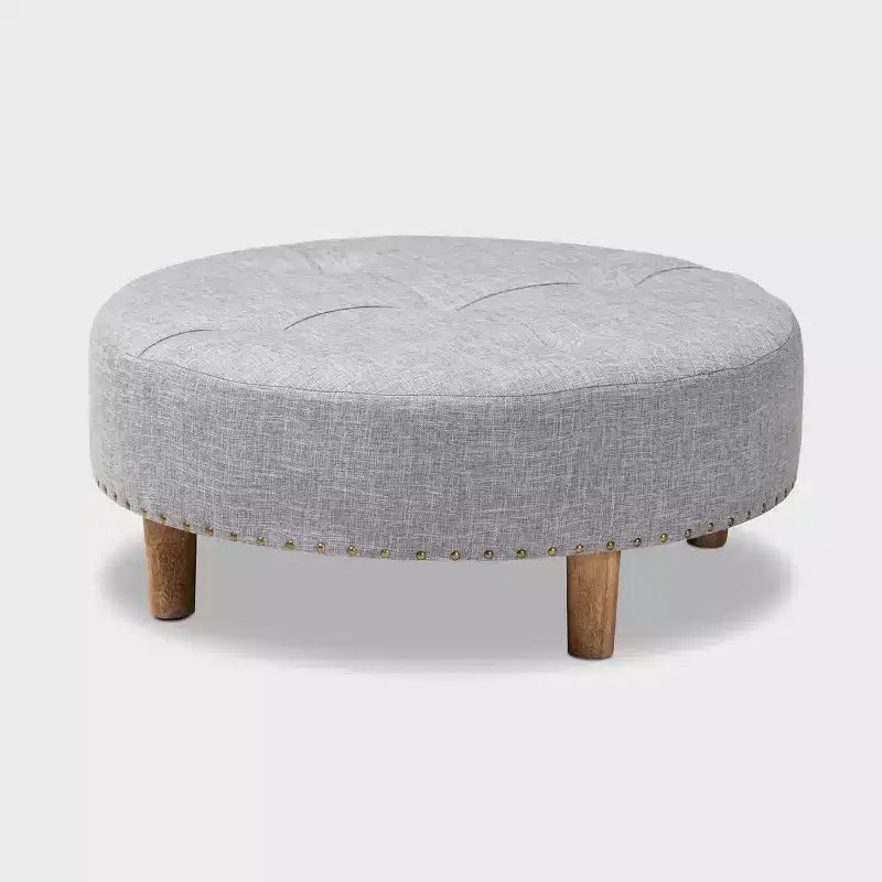 Pouf rotondo rivestito in tessuto, con parte superiore trapuntata e borchie decorative