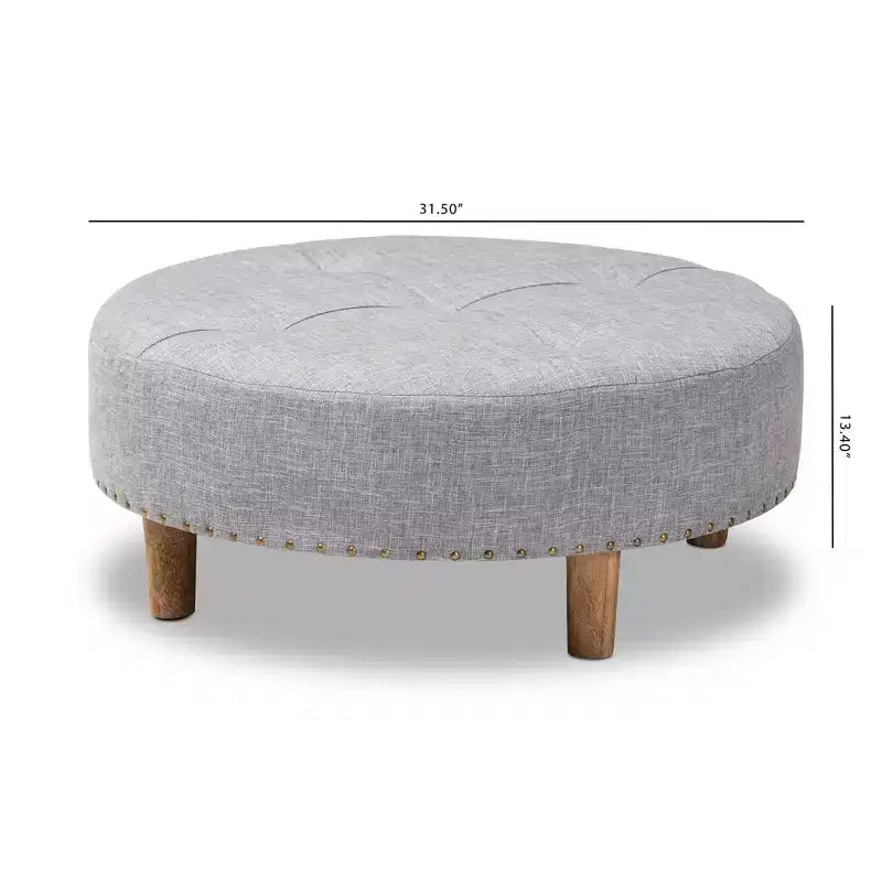 Pouf rotondo rivestito in tessuto, con parte superiore trapuntata e borchie decorative