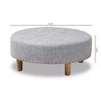 Pouf rotondo imbottito con piano trapuntato e bordatura con borchie